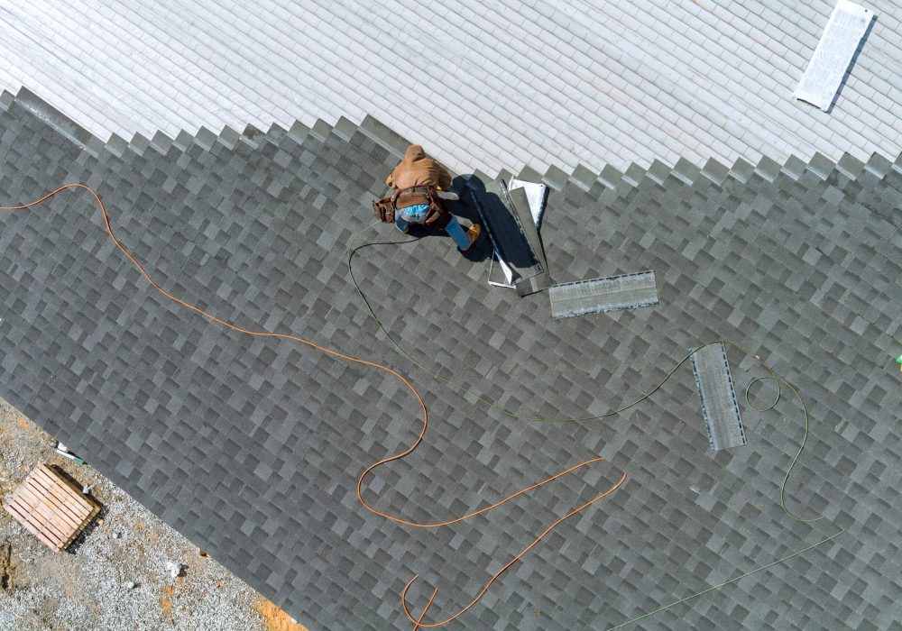 Aerial top view a asphalt shingles installation on the roof roofer is nailing asphalt shingles to roofing construction