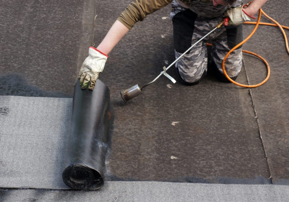 A worker doing roofers welding line with a gas torch